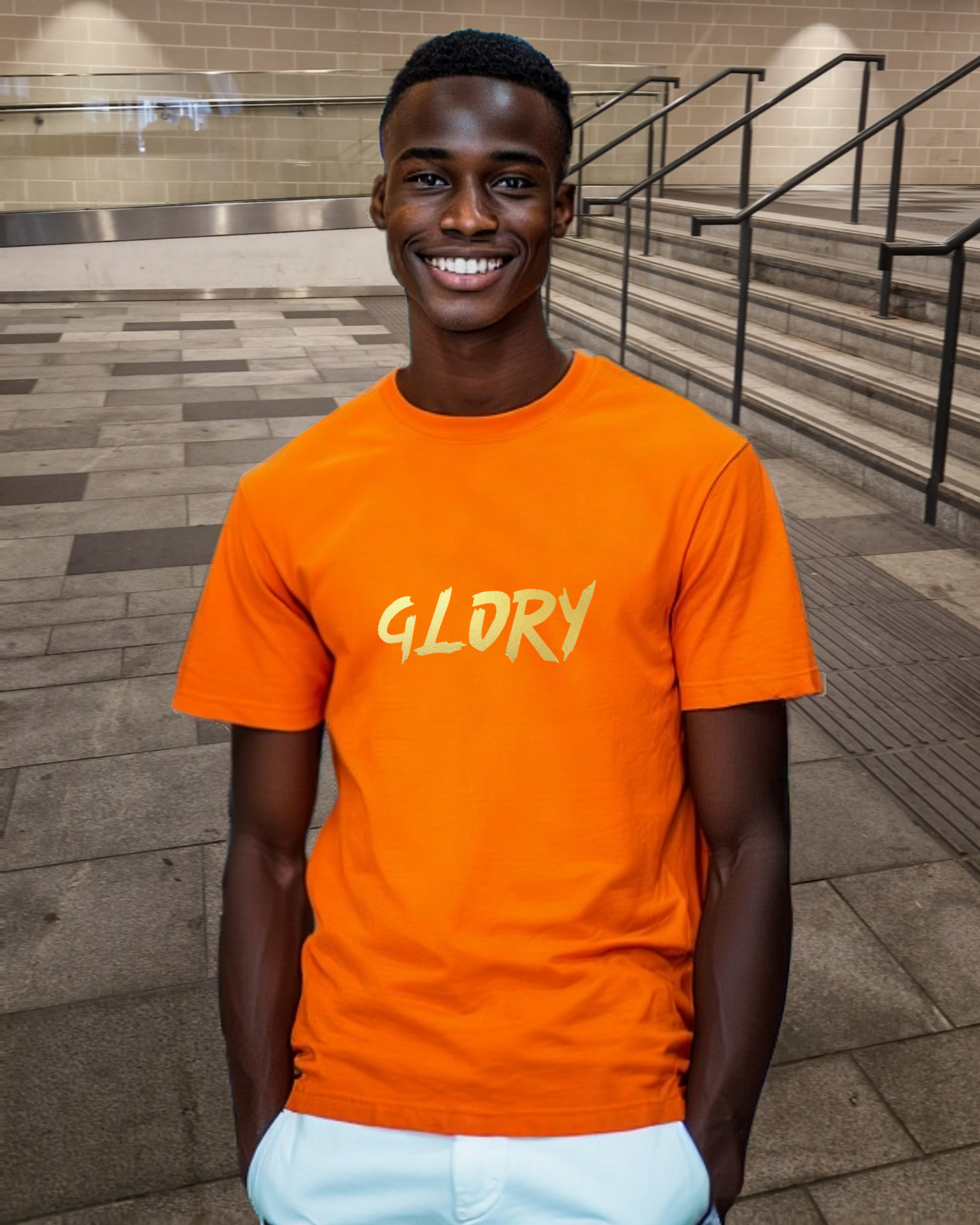 A man wearing an orange t-shirt with a gold "Glory" text logo printed on the front.