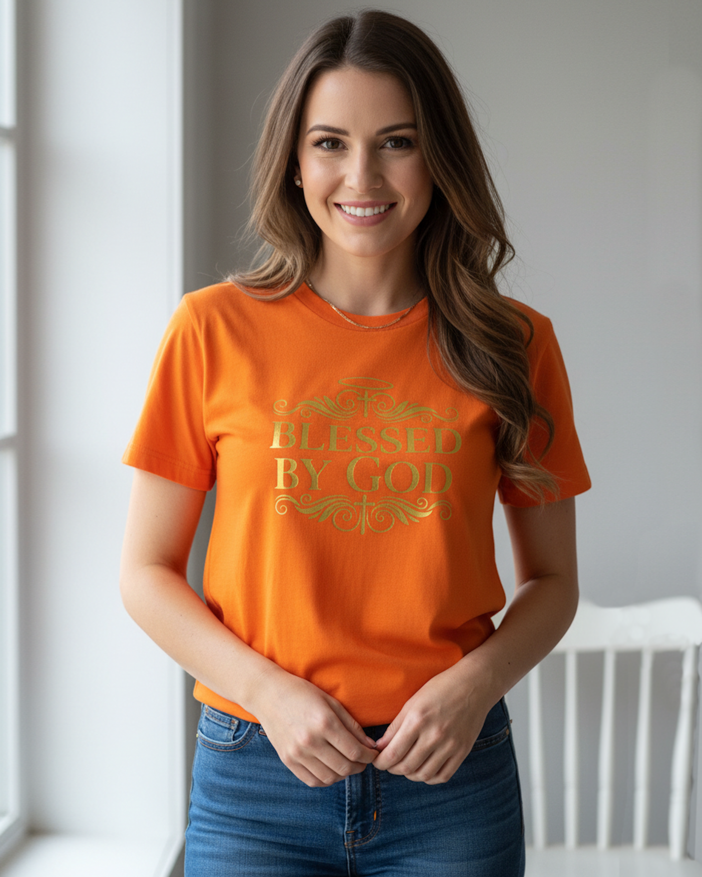 Woman wearing an orange t-shirt with gold 'Blessed by God' text logo on the front, standing indoors.