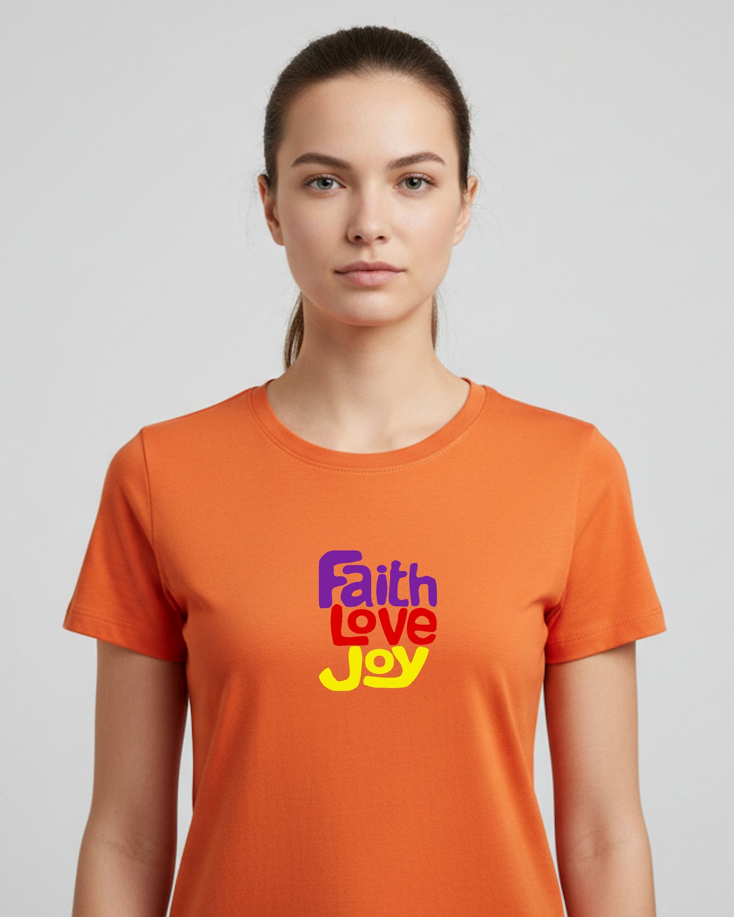 Woman wearing an orange t-shirt with 'Faith Love Joy' text on a plain background