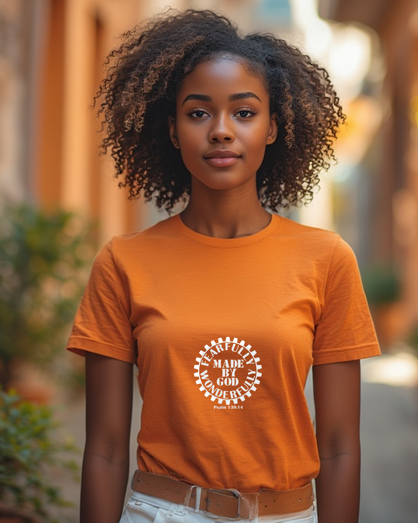 A man wearing an orange t-shirt with a white Heavenly Dreamwear logo with the text "Fearfully Wonderfully Made by God" inside a geared wheel.