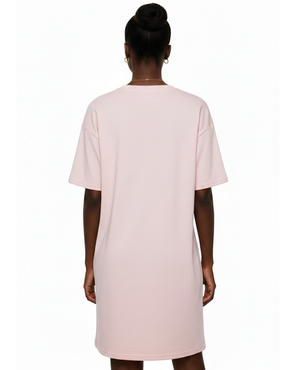 Woman wearing a light pink t-shirt dress against a white background