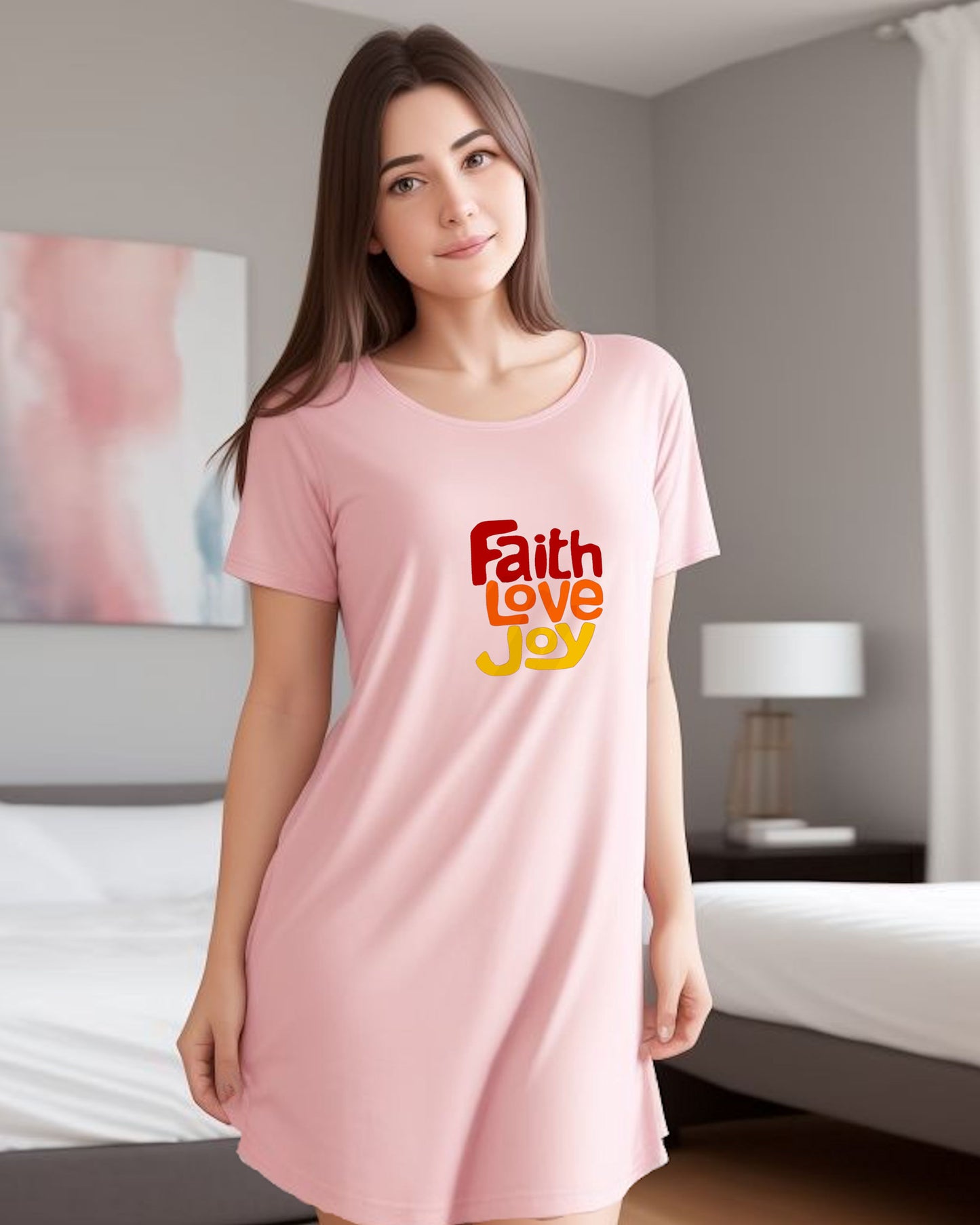 Woman wearing a pink nightshirt with 'Faith Love Joy' text logo with red, orange, yellow in a bedroom setting.