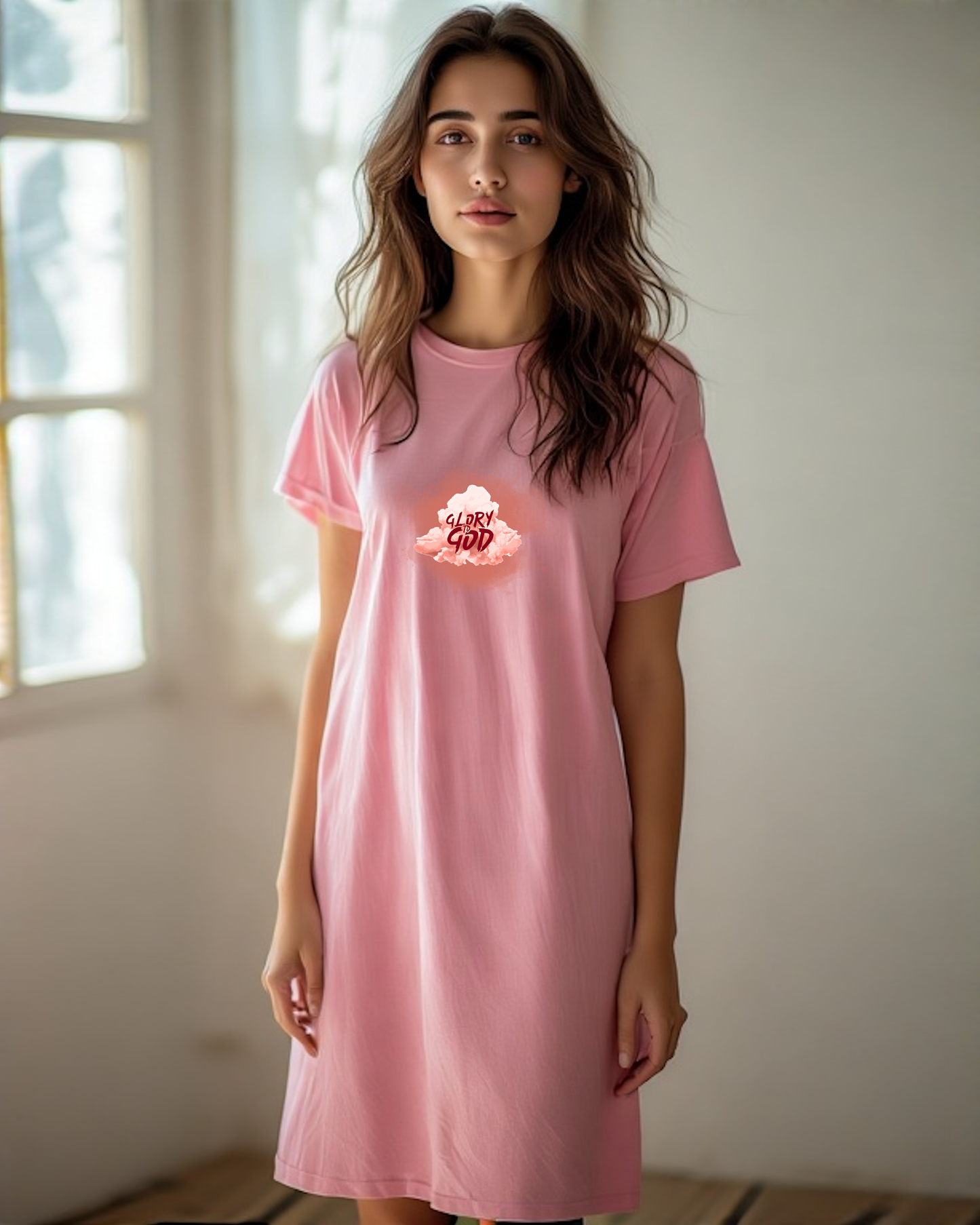 A woman in a shop wearing a pink Heavenly Dreamwear T-shirt dress with a logo containing the Text, "Glory to God" within a cloud.