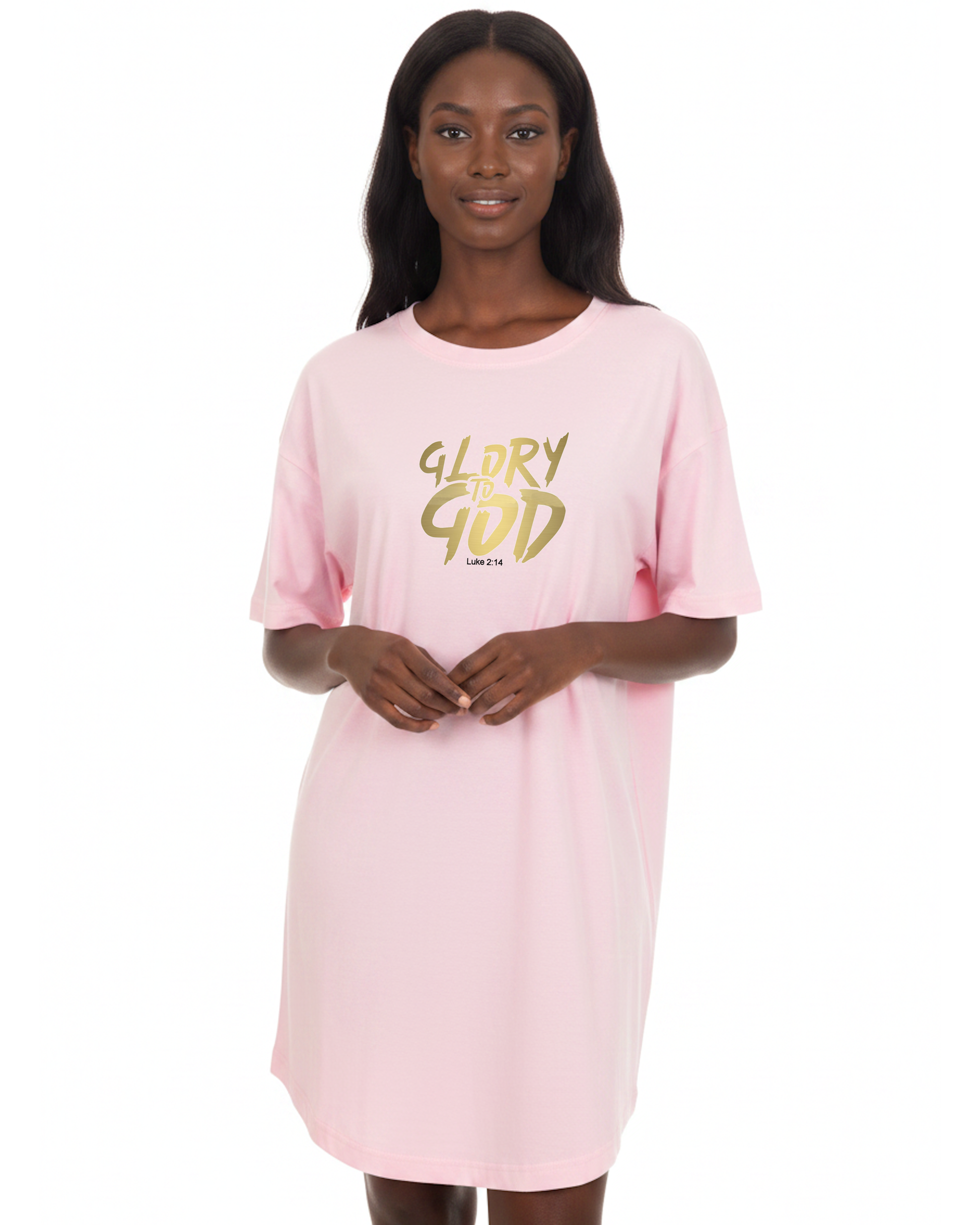A woman modeling an oversized pink short-sleeve t-shirt dress with 'GLORY TO GOD' printed in gold across the chest, set against a white background.