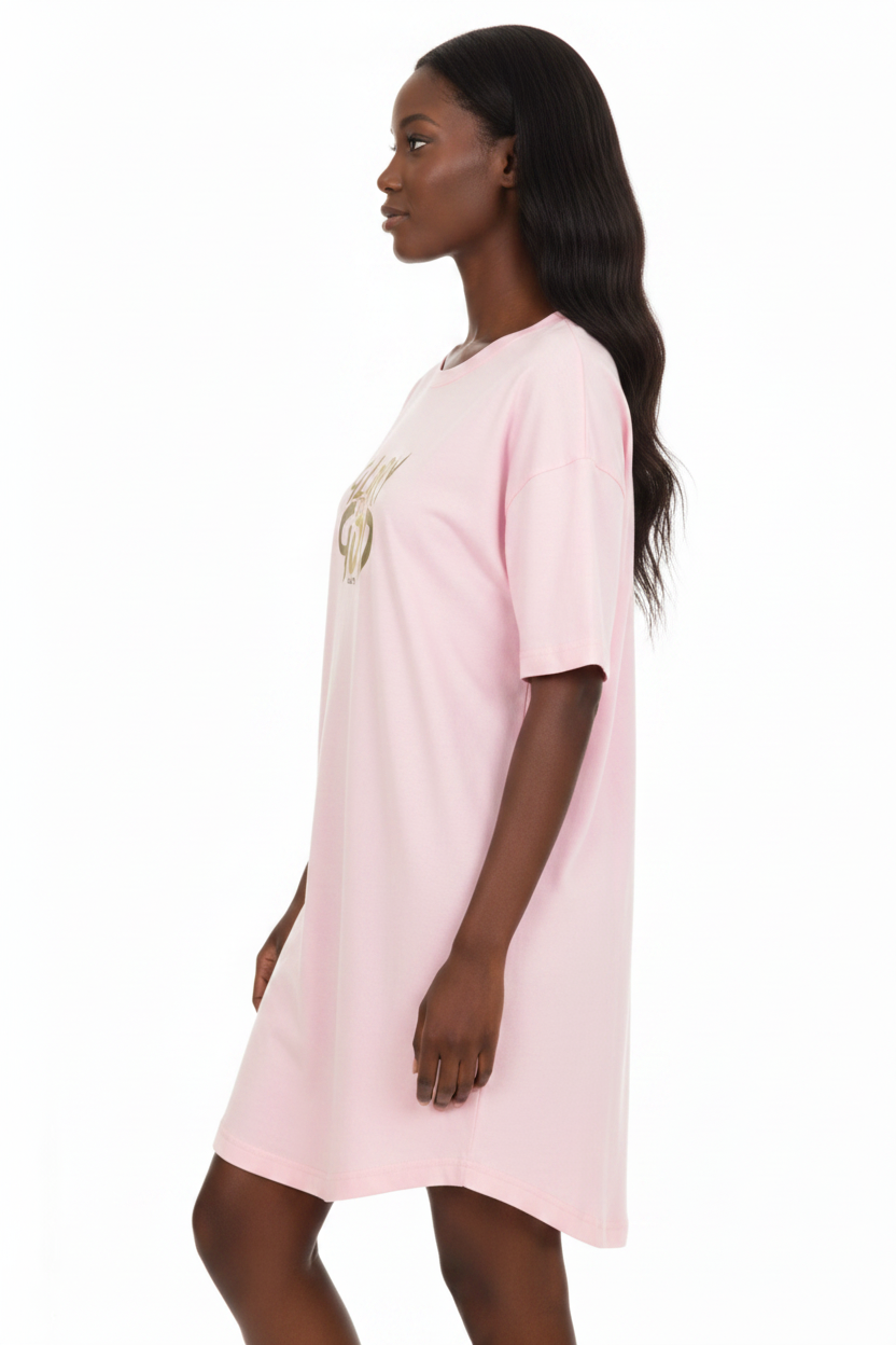 A woman wearing a light pink short-sleeve t-shirt dress with a gold graphic print on the chest, shown from a side profile against a white background.