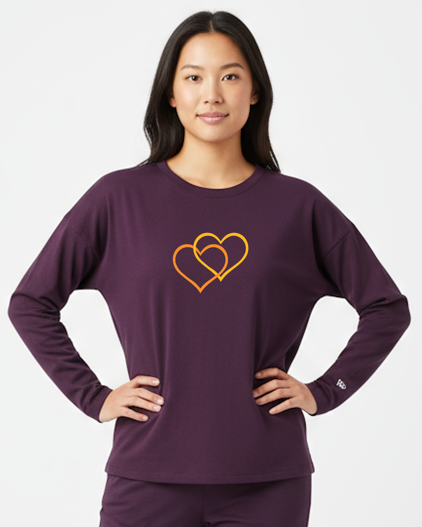 Woman wearing a purple long-sleeve shirt with a orange and yellow dual-heart design on a white background