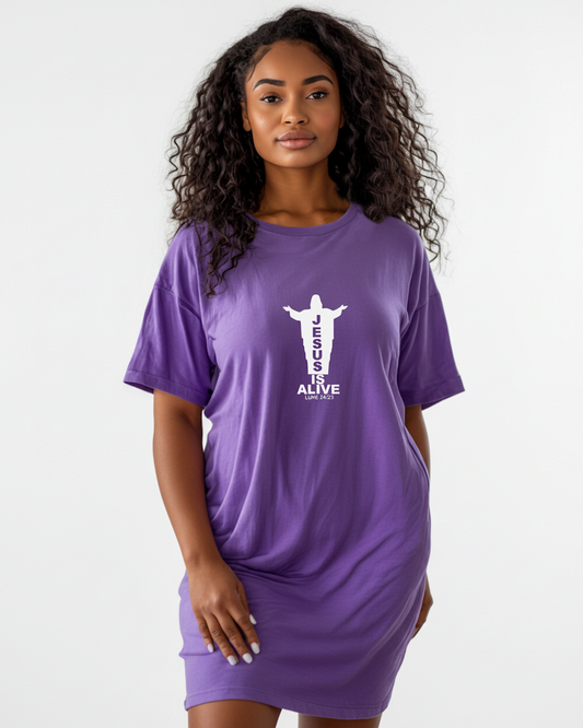Woman wearing a purple t-shirt dress with a silhouette of Jesus and text, 'JESUS IS ALIVE' against a white background.