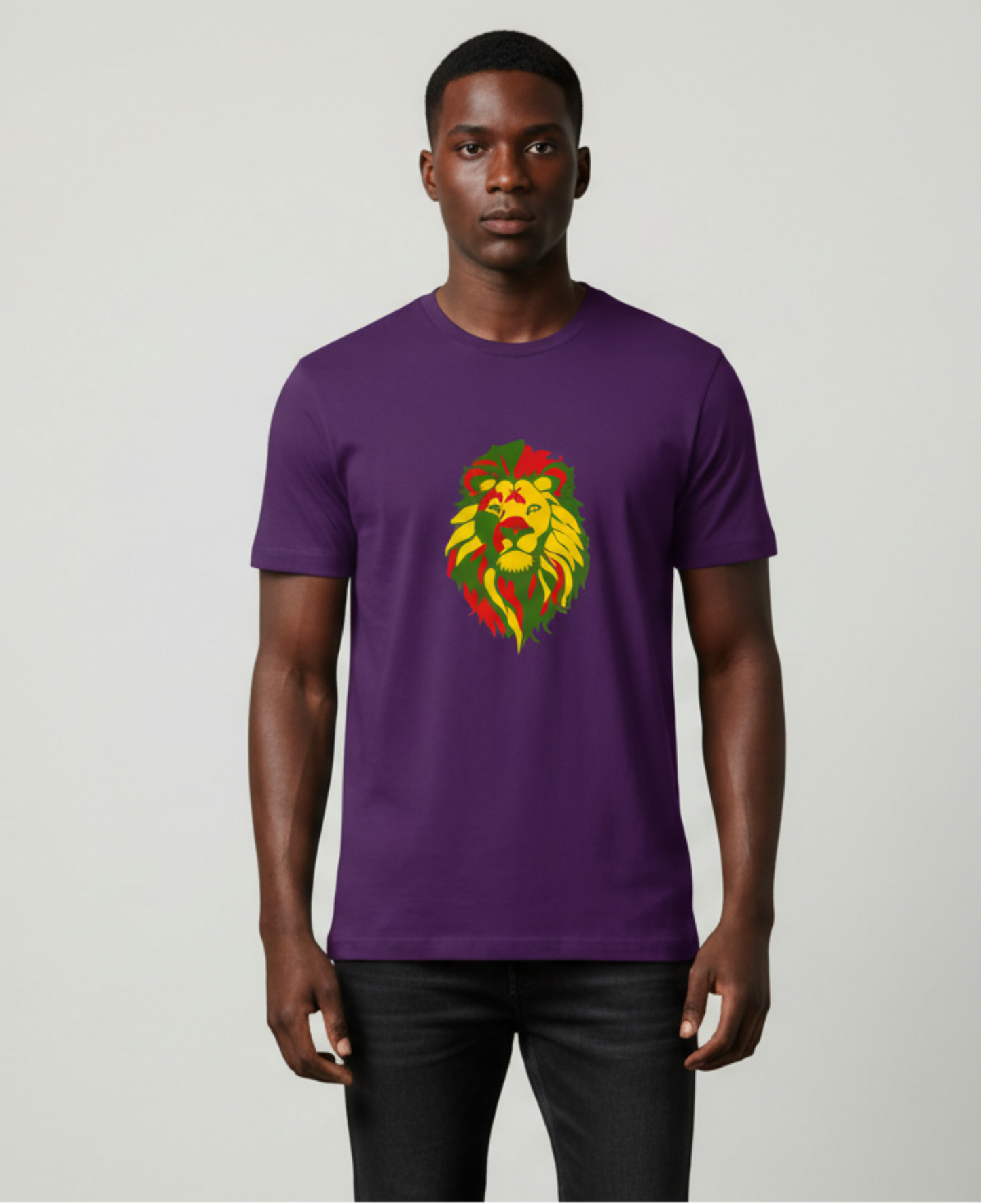 A man wearing a purple crewneck t-shirt with a red, yellow and green lion graphic on the chest, paired with black jeans, standing against a light gray background.