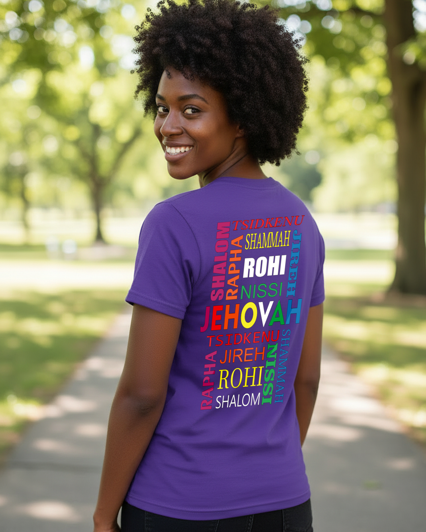 Rear view of woman wearing a purple t-shirt with colorful text in a park.