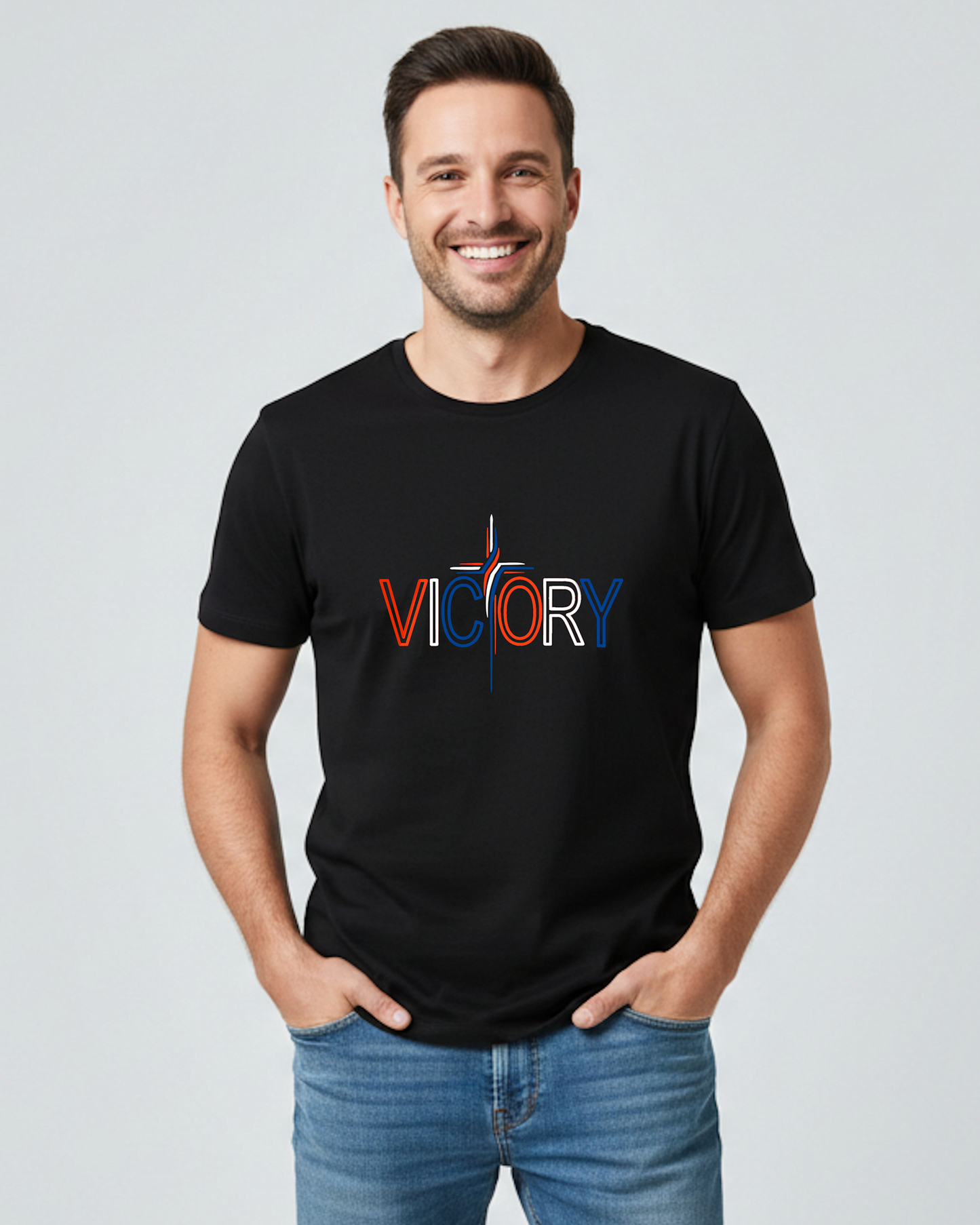 A man wearing a black t-shirt with a red, white, and blue Heavenly Dreamwear "Victory" logo printed on the front. he 'T' is made in the shape of a stylish cross, all against a grey background.