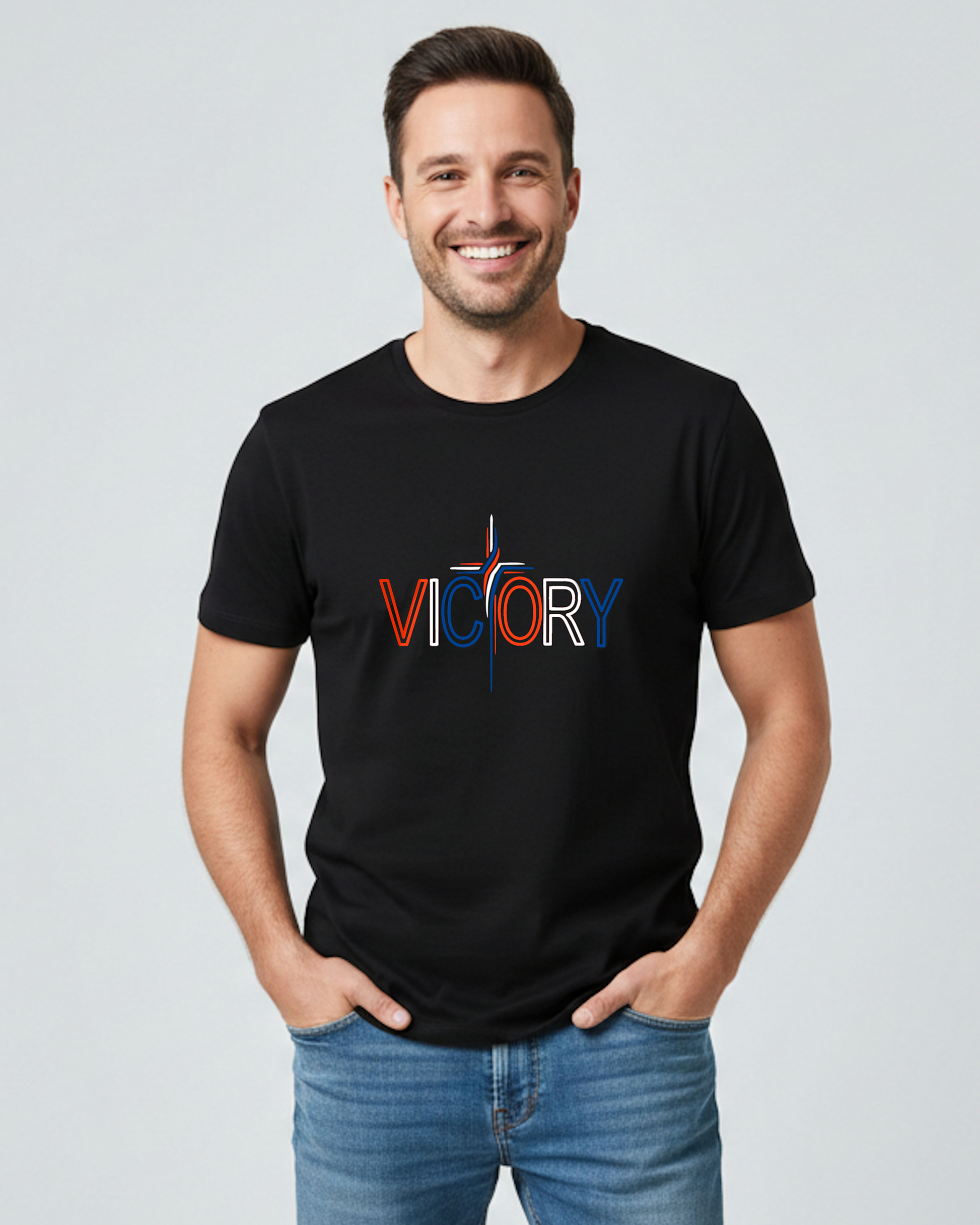 A man wearing a black t-shirt with a red, white, and blue Heavenly Dreamwear "Victory" logo printed on the front. he 'T' is made in the shape of a stylish cross, all against a grey background.