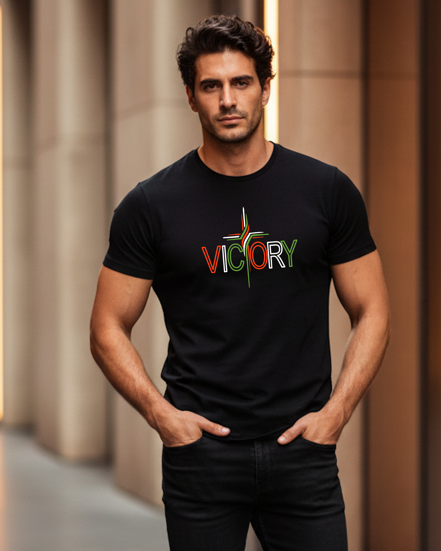 A man wearing a black short-sleeve t-shirt with a colorful 'VICTORY' graphic on the chest, standing indoors.