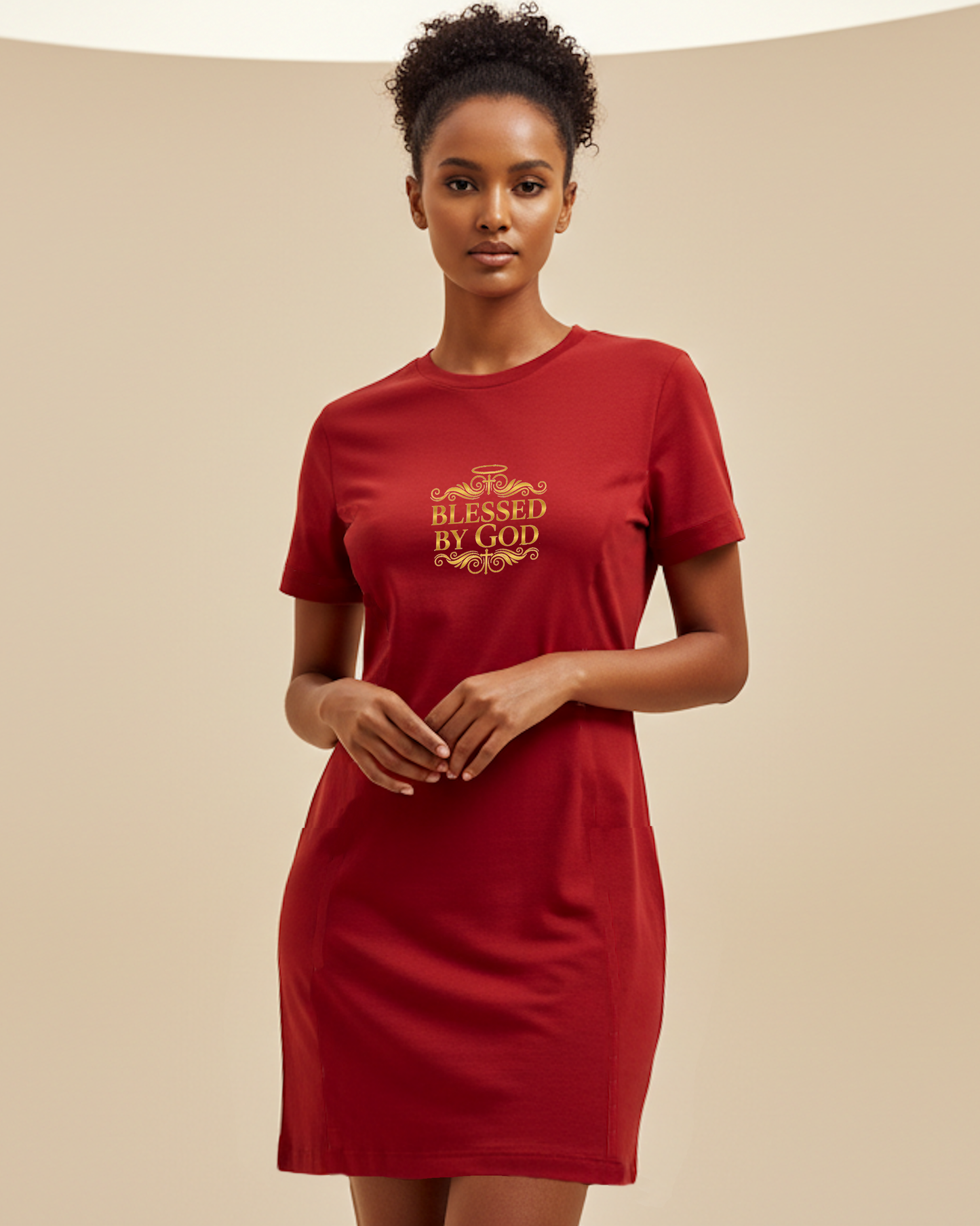 Woman wearing a red t-shirt dress with 'Blessed by God' text in gold, against a beige background.