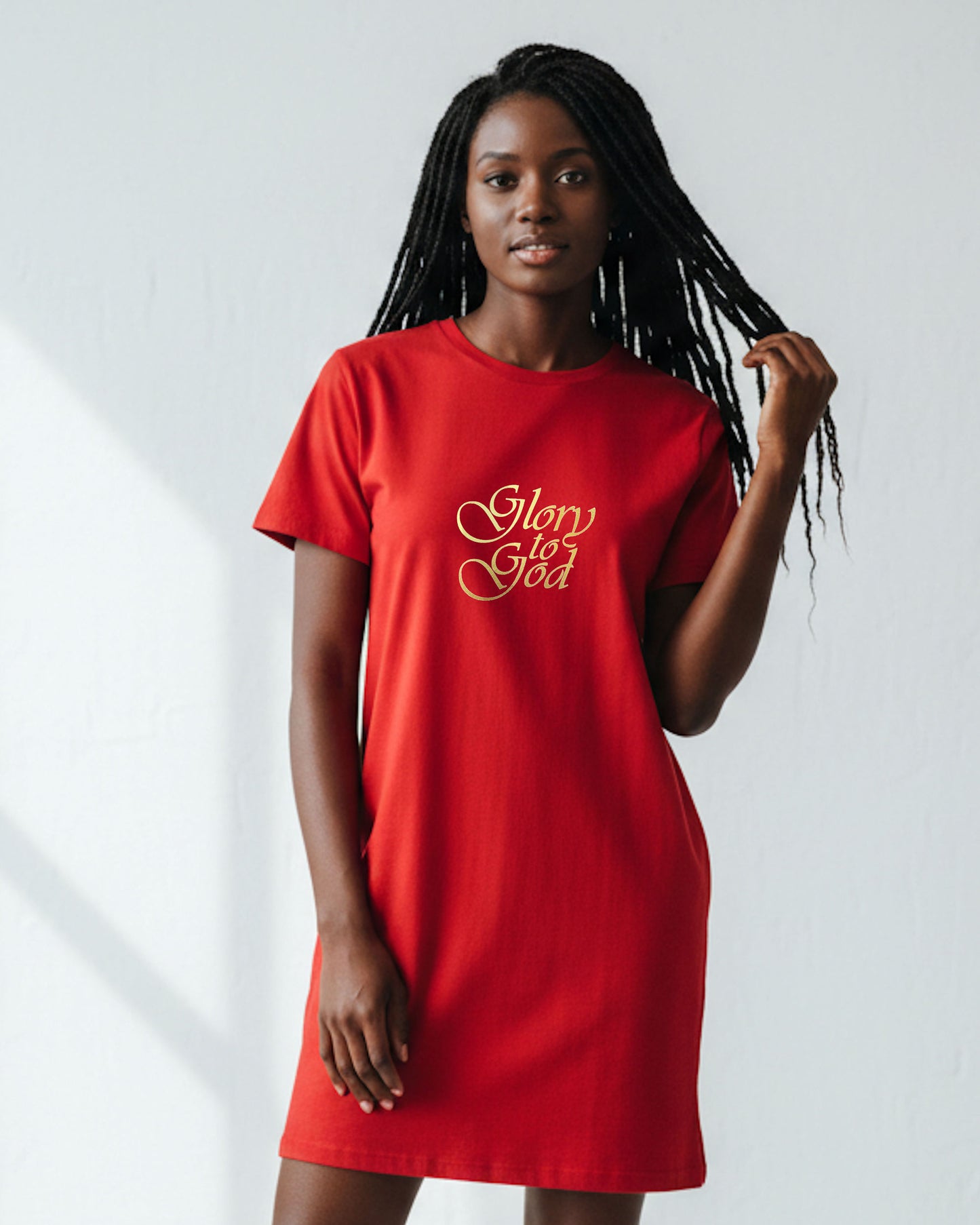 A woman wearing a red t-shirt dress with gold text the says, 'Glory to God' against a white background