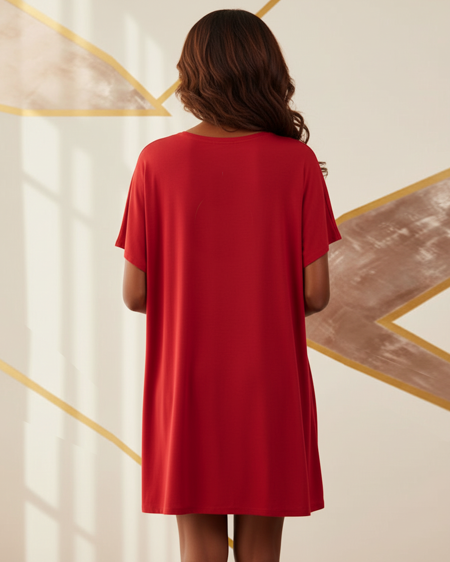 Woman wearing a red t-shirt dress against a decorative wall.