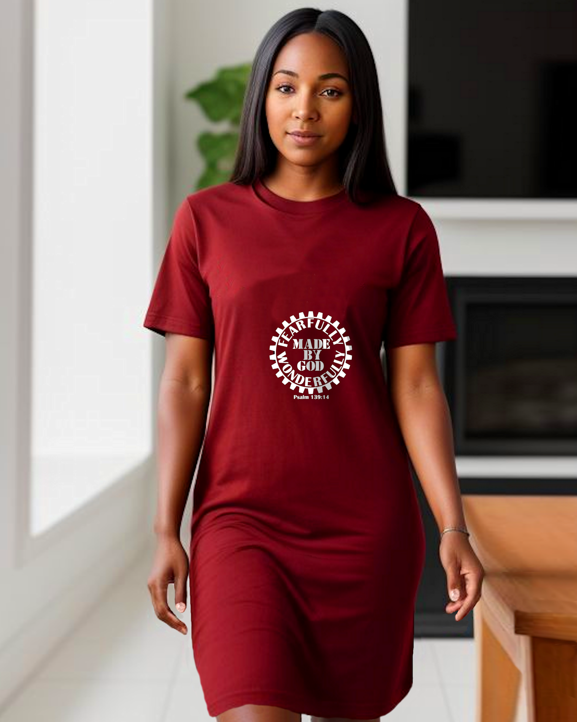 A woman standing in a kitchen wearing a red t-shirt dress with a white Heavenly Dreamwear logo comprised of  text "Fearfully Wonderfully Made by God" inside a geared wheel.