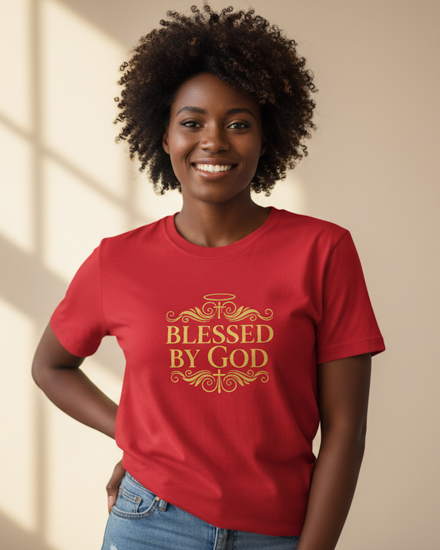 Woman wearing a red t-shirt with a gold "Blessed By God" text logo against a beige wall background
