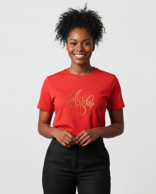 A smiling woman with curly black hair wearing a bright red crewneck t-shirt with 'Call to Worship' printed in gold cursive across the chest, paired with black pants, against a light gray studio background.