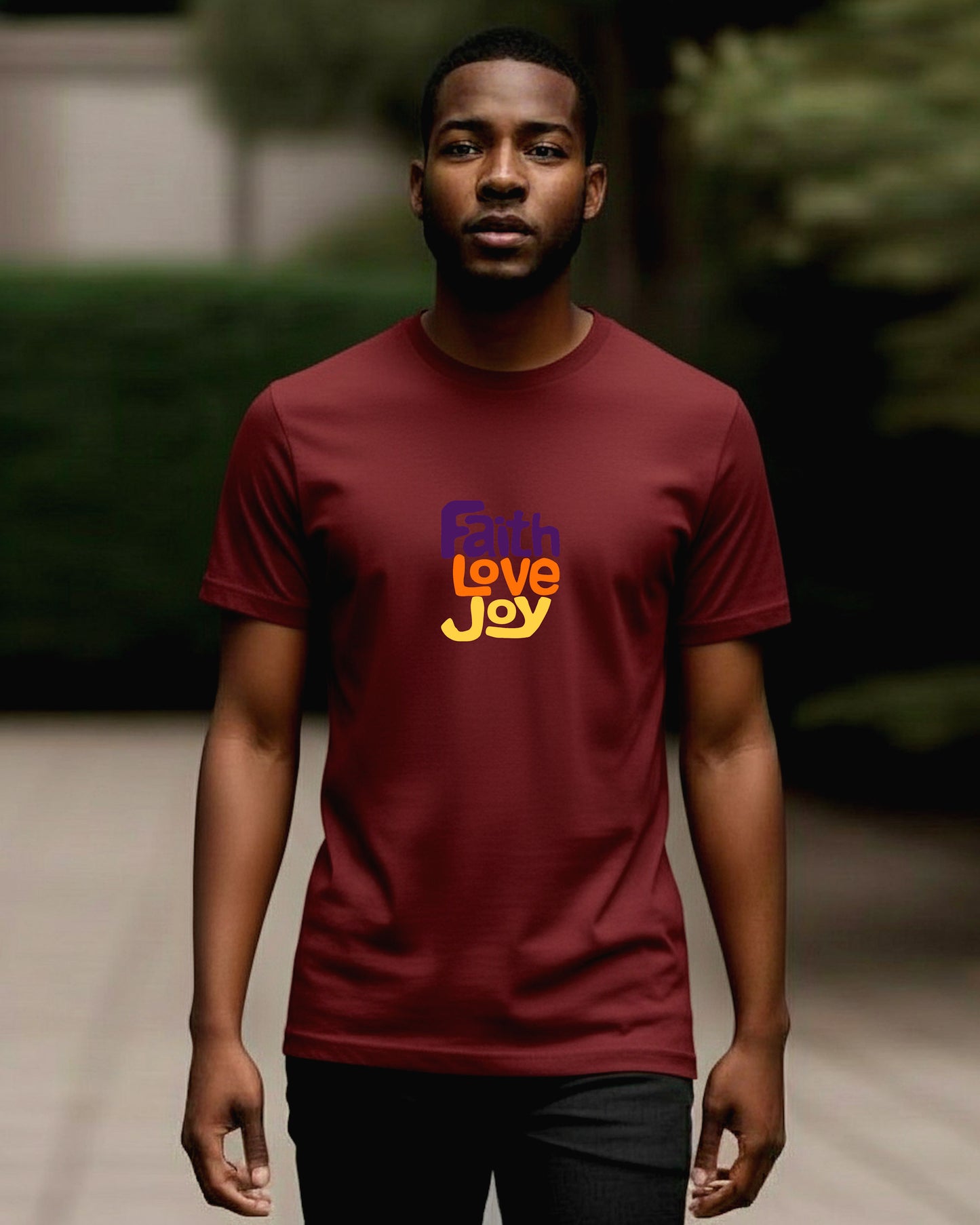 Man wearing a redt-shirt with 'Faith Love Joy' text outdoors.