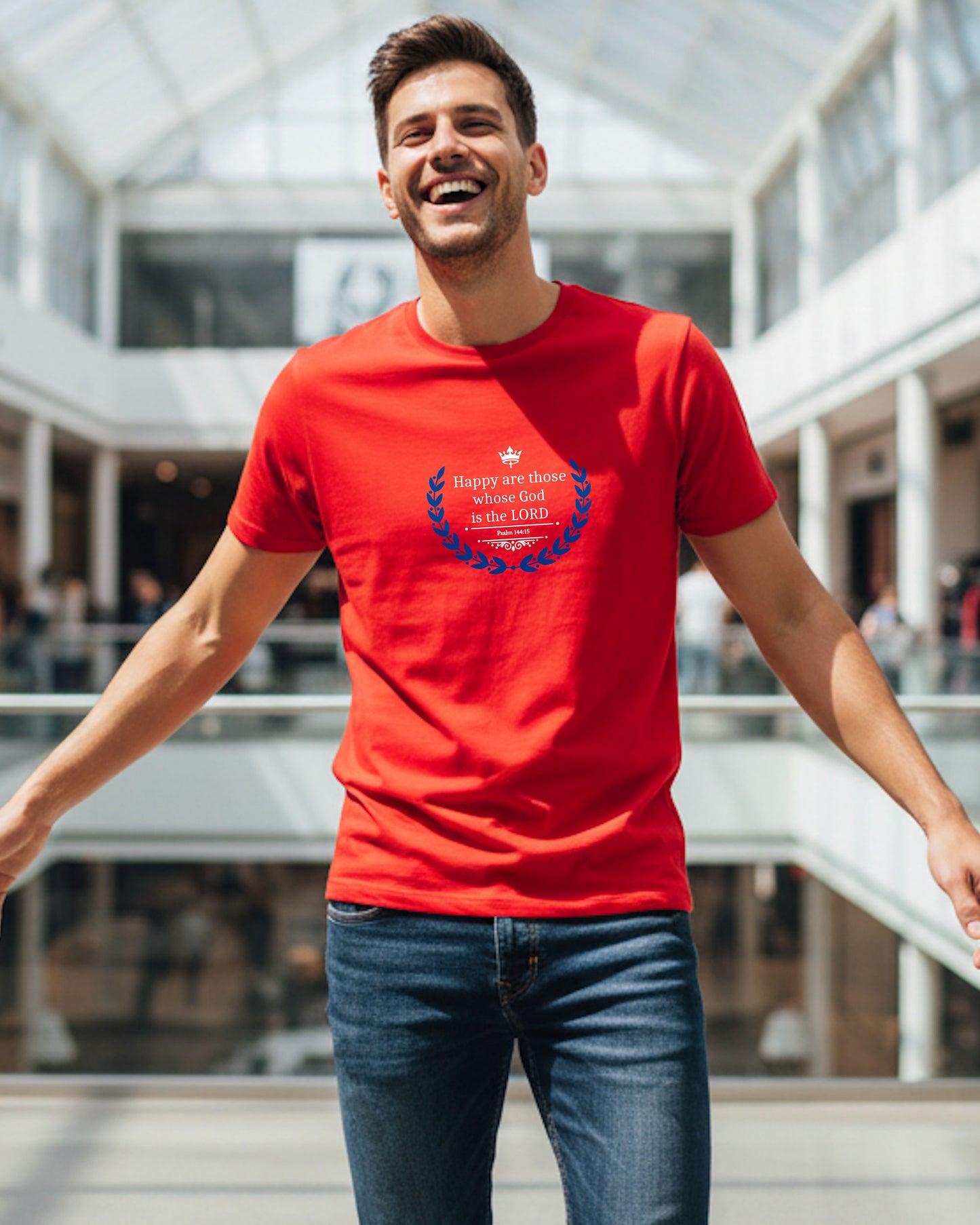 Man wearing a red t-shirt with a white text and blue laurel graphic design in a shopping mall setting
