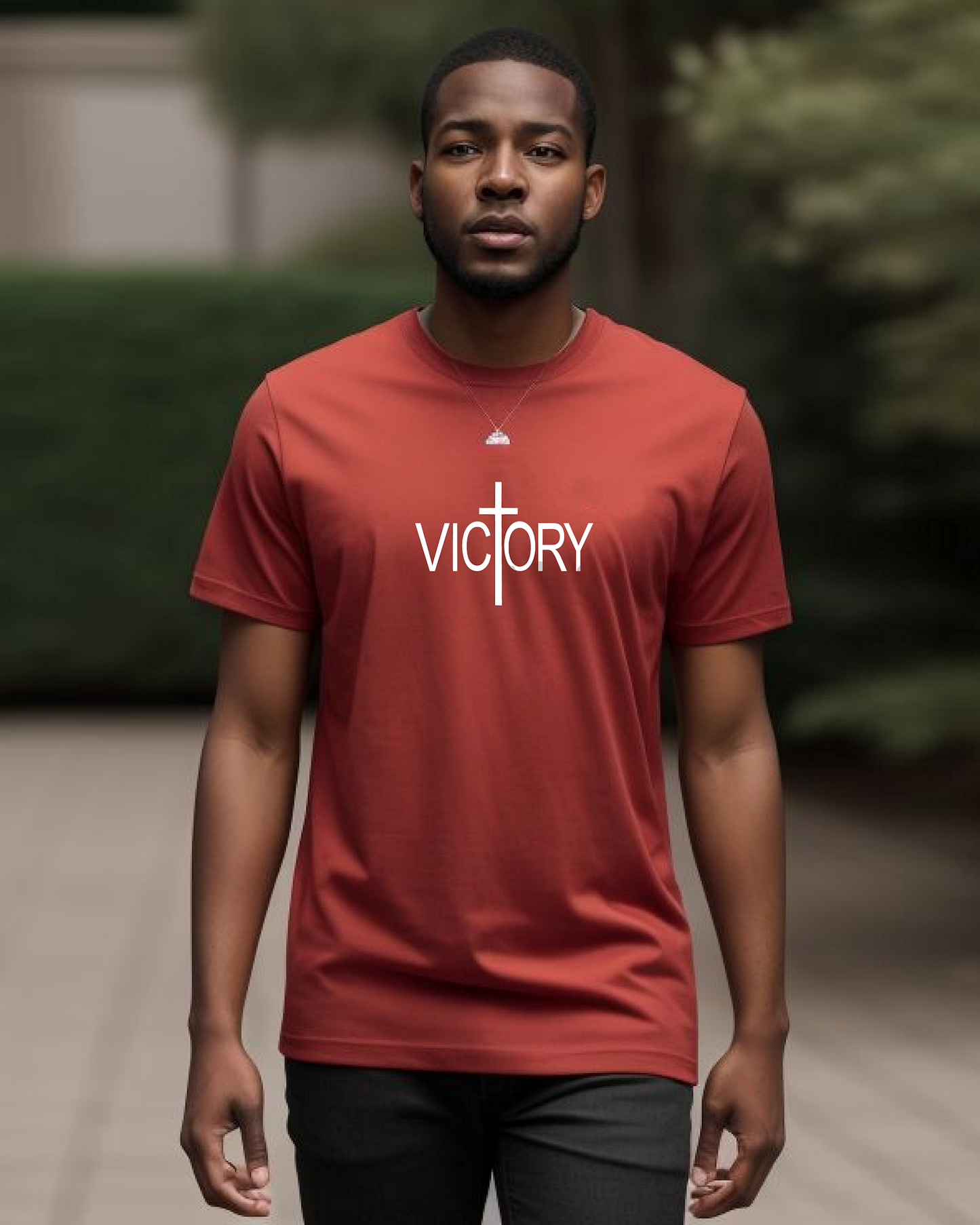 A man wearing a red t-shirt with a white Heavenly Dreamwear "Victory" logo printed on the front, standing in a garden.