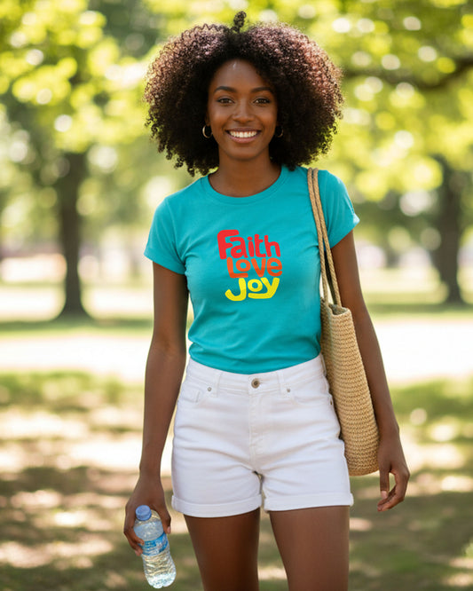 Woman wearing a teal t-shirt with a Heravenly Dreamwear 'Faith Love Joy' logo in a park.