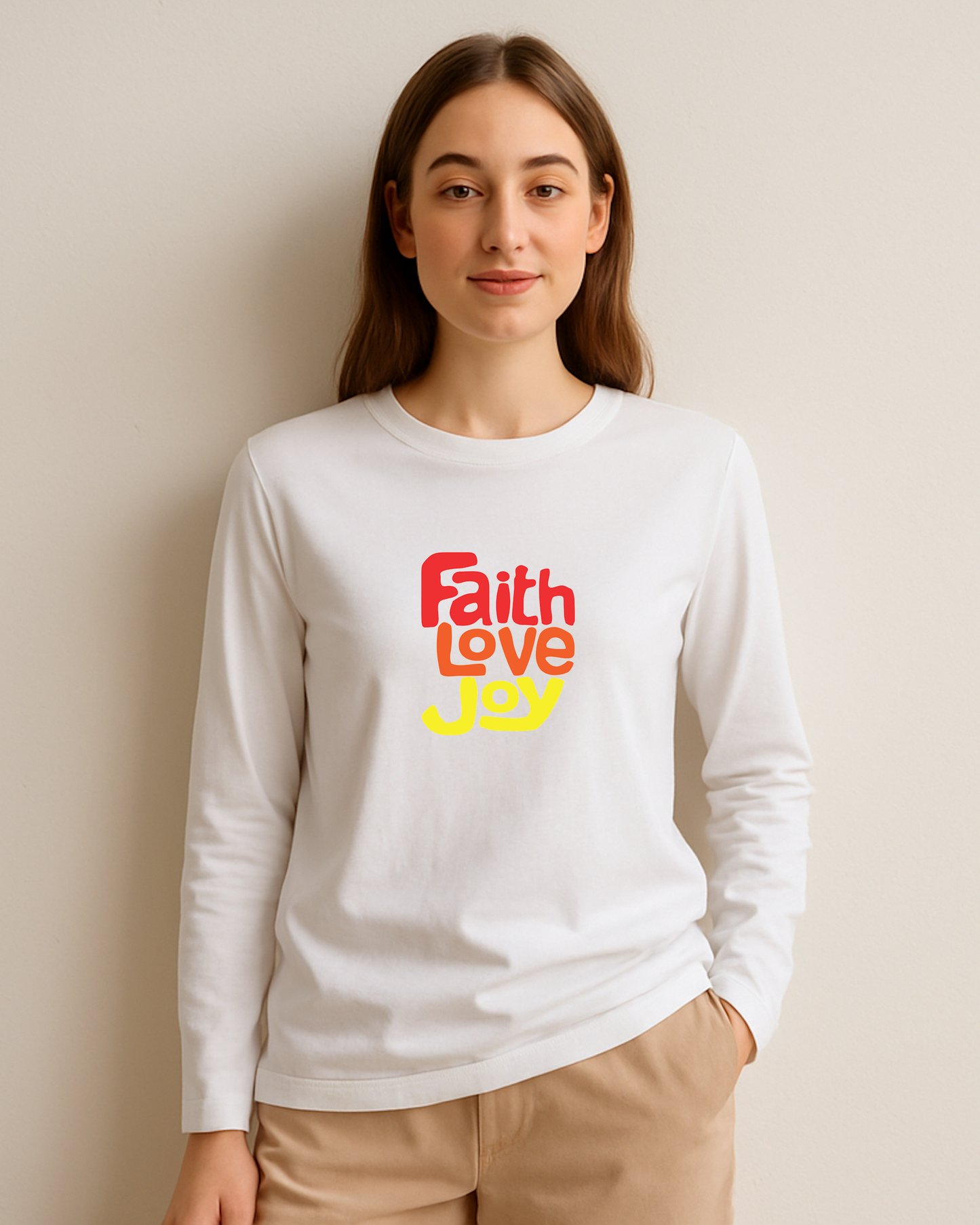 Woman wearing a white long-sleeve shirt with 'Faith Love Joy' text in red, orange, and yellow against a plain background