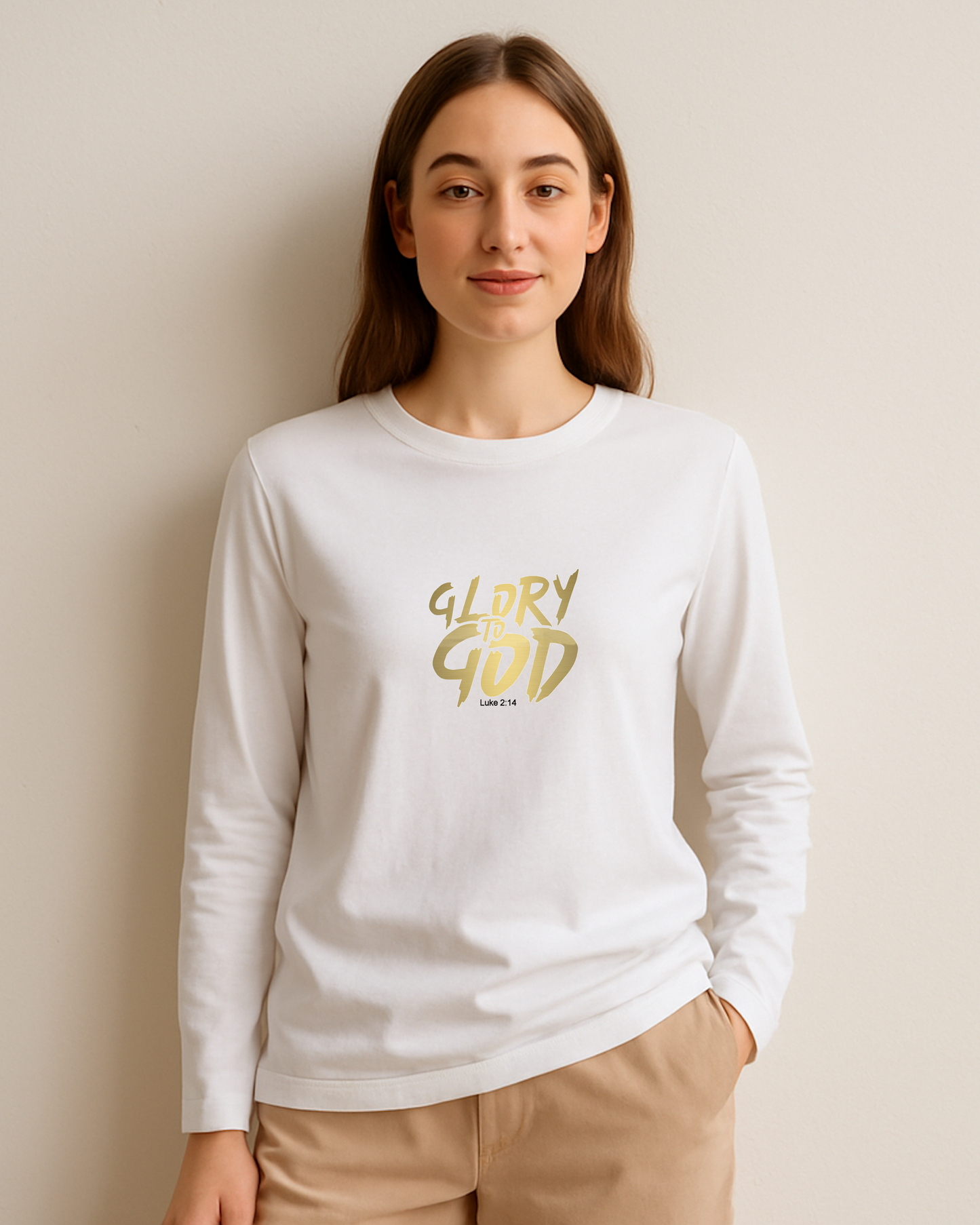 A woman wearing a white long-sleeve shirt with 'Glory to God' text in gold, inspired by scripture from Luke 2:14.