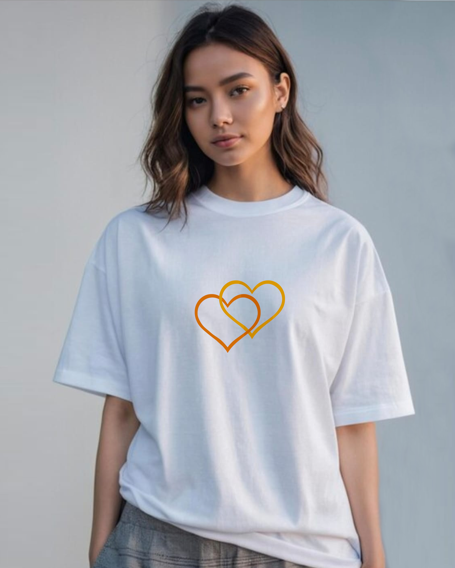 A woman wearing a white t-shirt with a Heavenly Dreamwear logo comprised of an orange and yellow inter-twinned hearts.
