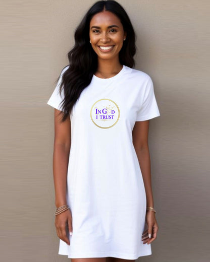 Woman wearing a white t-shirt dress with a gold ring logo and purple text, 'In God I Trust', on a plain background