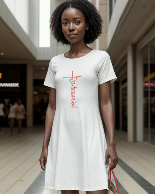 A woman in a shopping centre wearing a white t-shirt dress with an elaborate  Heavenly Dreamwear designed 'Redeemed' white logo printed on the front. 