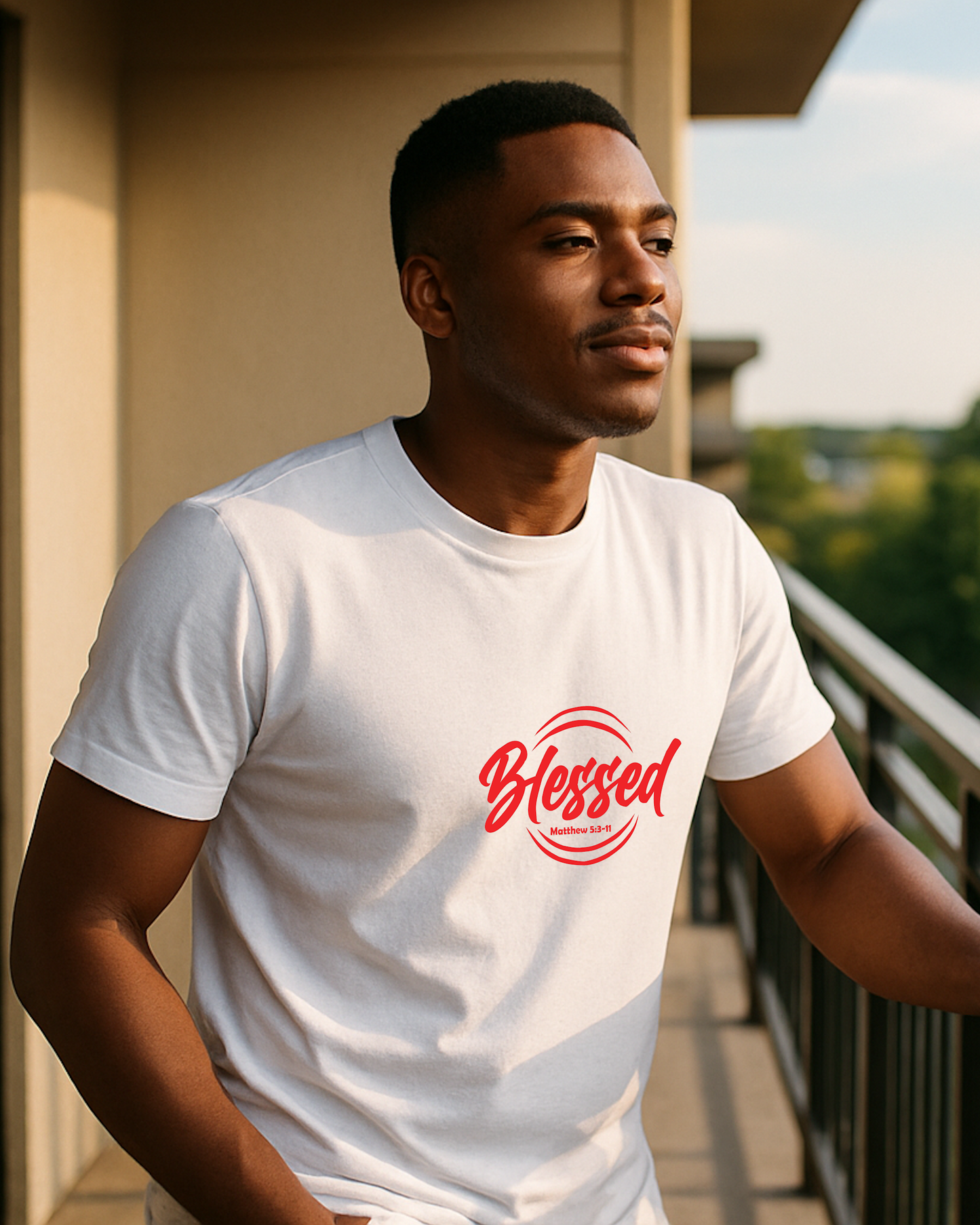 A young man wearing a white t-shirt with a red text logo that says 'Blessed' on a balcony.