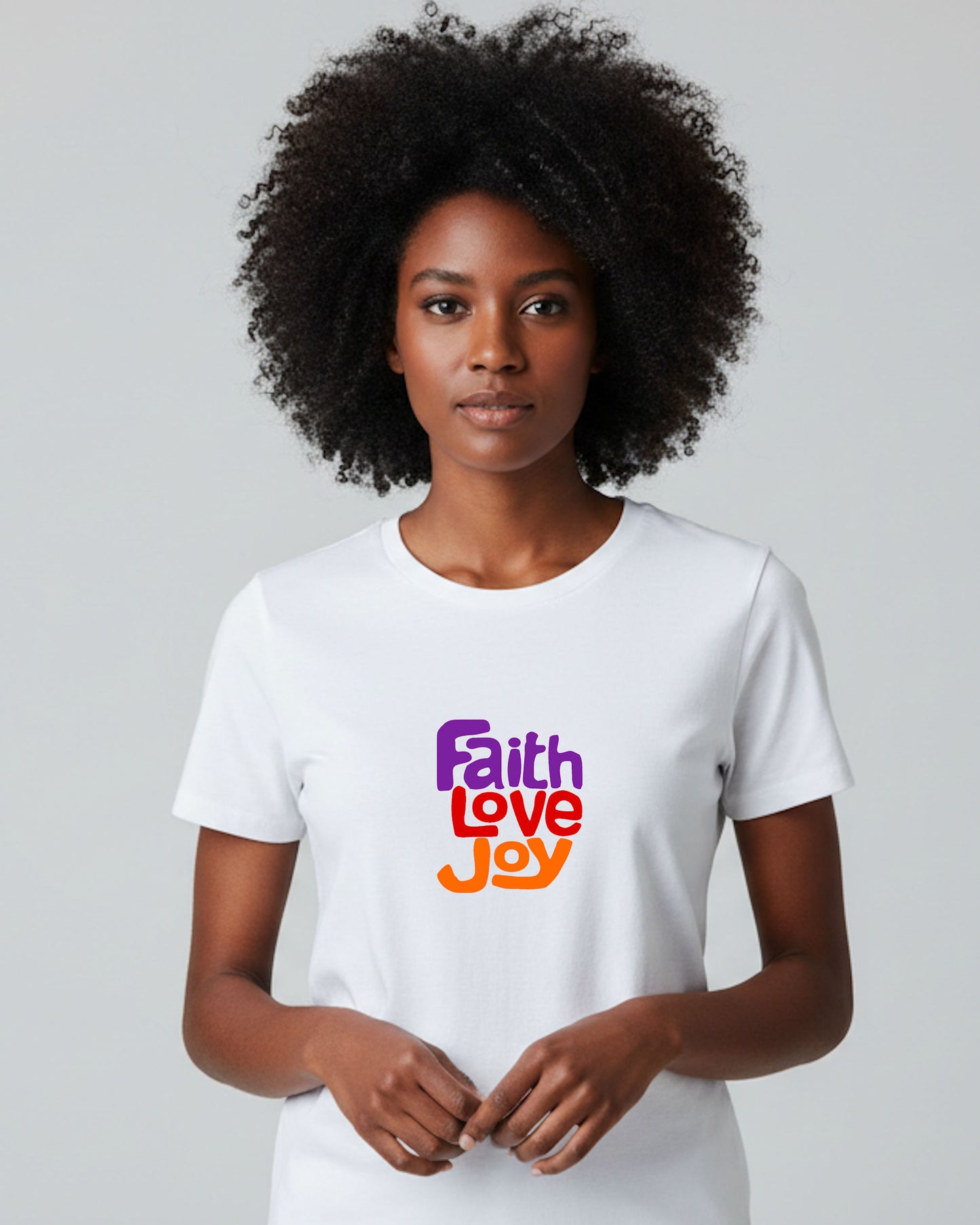 Woman wearing a white t-shirt with purple, red and orange 'Faith Love Joy' text on a plain background