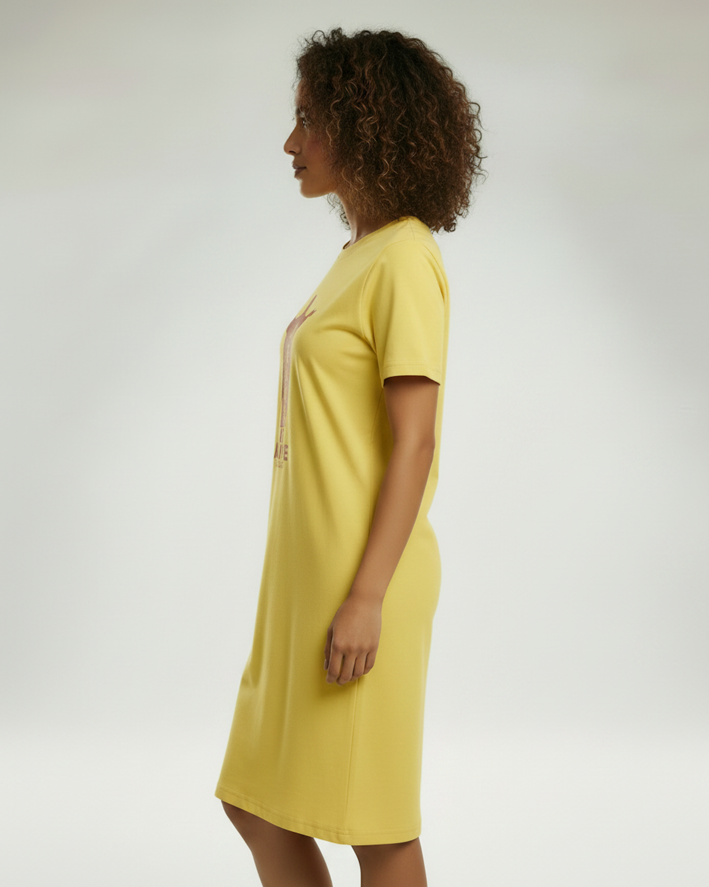 Side view of a woman wearing a yellow t-shirt dress.