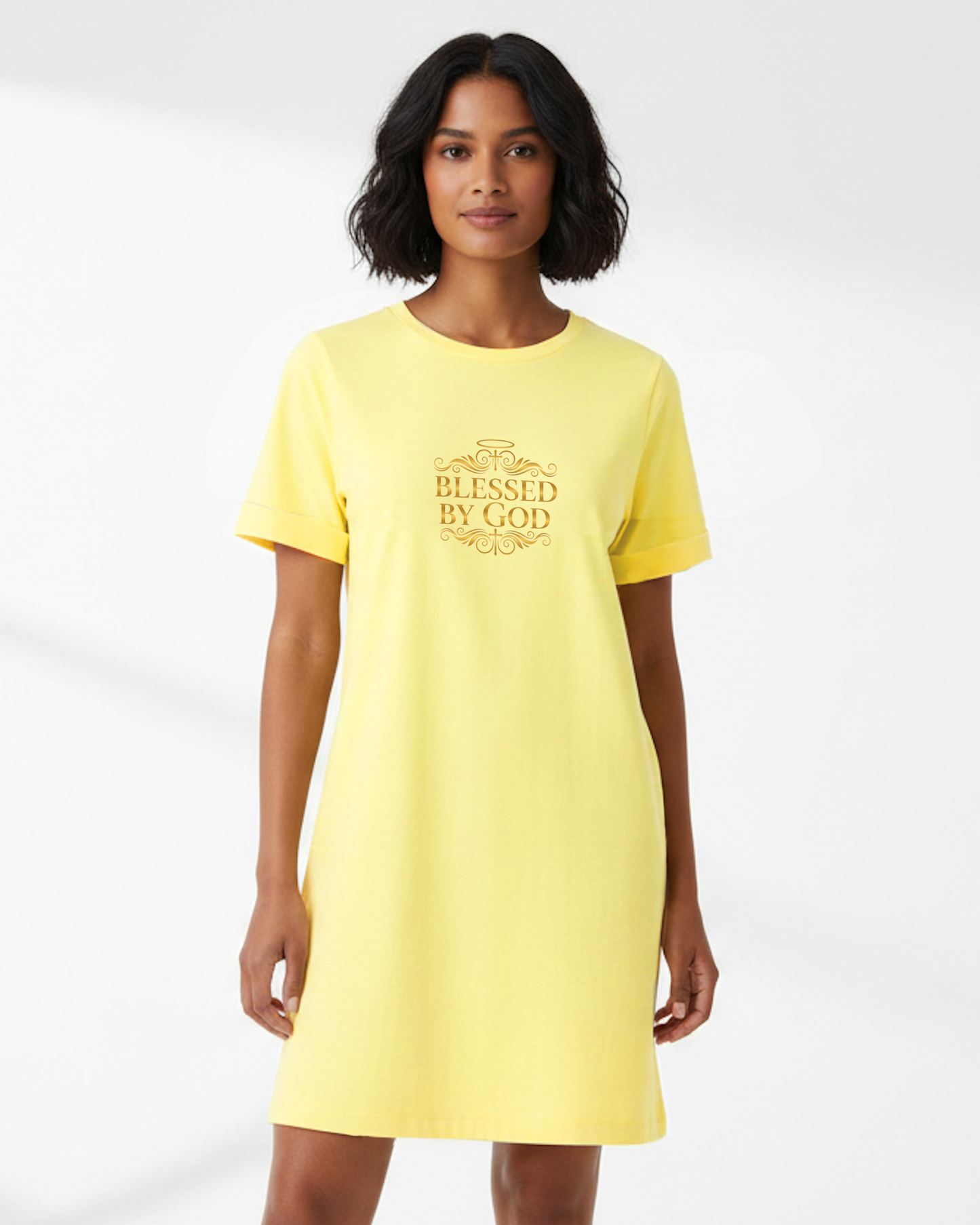 Woman wearing a yellow t-shirt dress with 'Blessed by God' text in gold, against a white background.