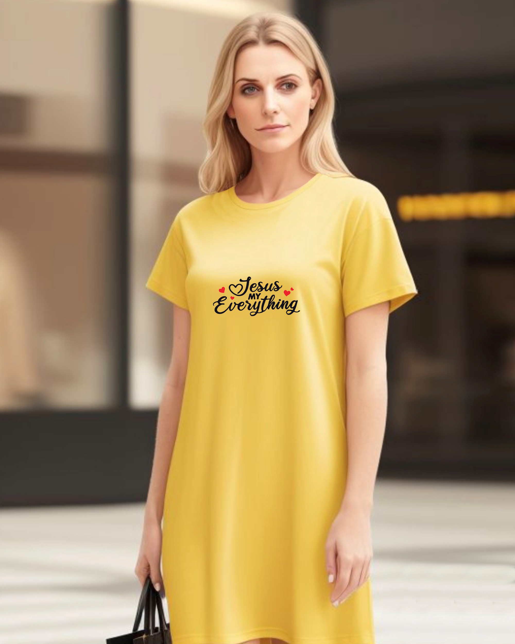 Woman wearing a yellow Heavenly Dreamwear t-shirt dress in a mall with a black text logo "Jesus MY Everything" with 4 red hearts printed on the dress.